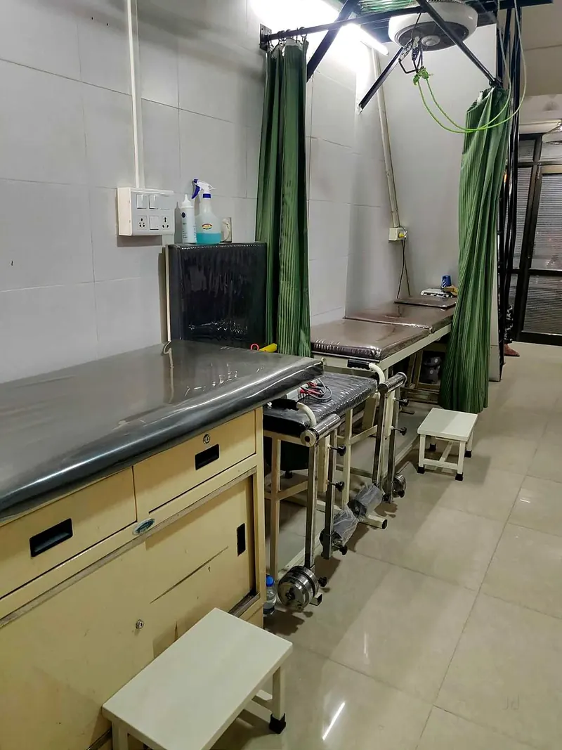 A row of treatment couches separated by green privacy curtains